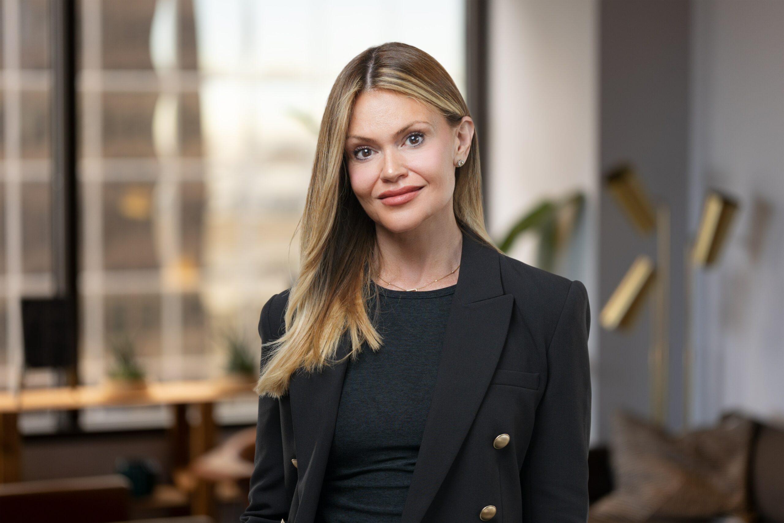 a woman in a black blazer standing in an office.